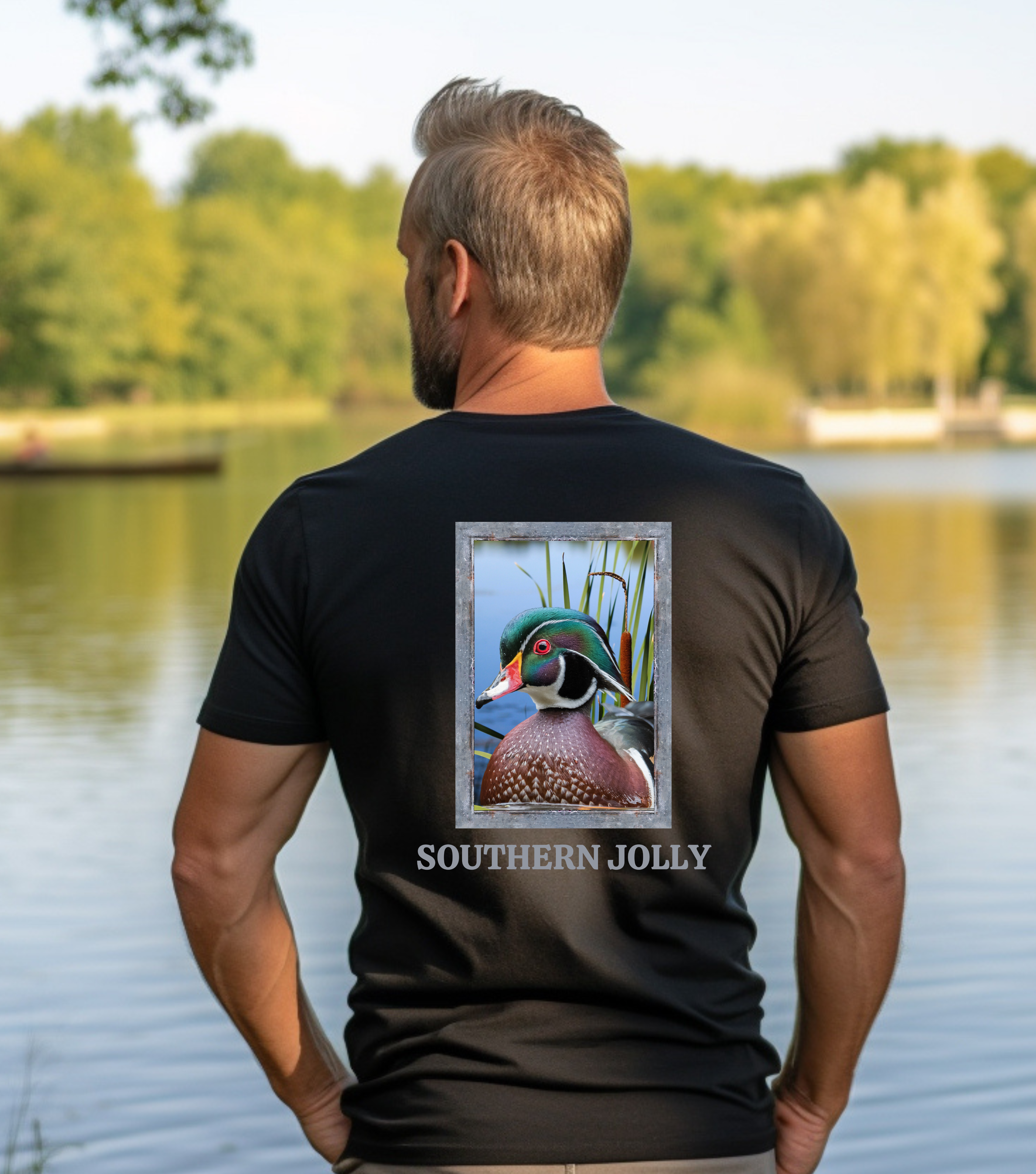 Man wearing a black t-shirt with a duck design and 'Southern Jolly' text by a lake.