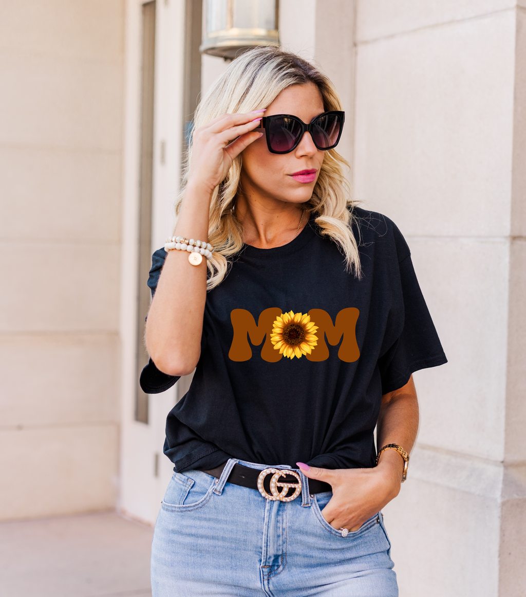 Woman wearing a black t-shirt with a MOM design featuring a sunflower.